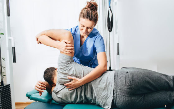 Physiotherapist treatment patient. She holding patient's hand, shoulder joint treatment