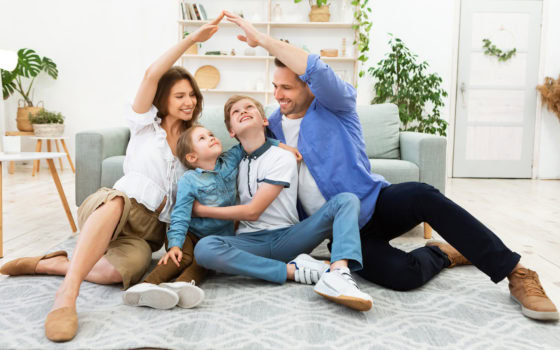 Young parents joining hands making roof sitting with children indoor